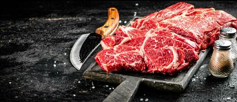 Raw beef on a cutting board with a knife. photo