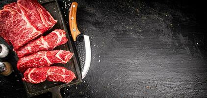 Raw beef on a cutting board with a knife. photo