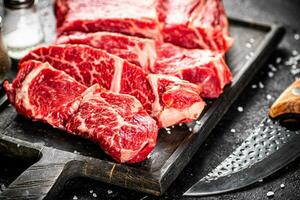 Raw beef on a cutting board with a knife. photo