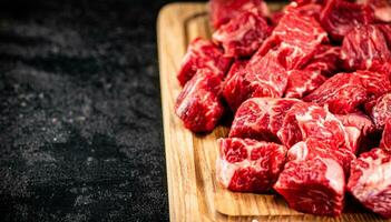 Raw pieces of beef on a wooden cutting board. photo