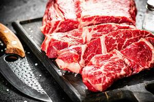 Raw beef on a cutting board with a knife. photo