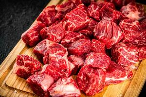 Raw pieces of beef on a wooden cutting board. photo