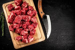 Chopped raw beef on a cutting board with rosemary and a knife. photo