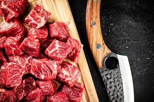 Raw pieces of beef on a wooden cutting board. photo