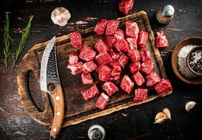 Raw pieces of beef on a cutting board with a knife. photo