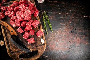 Cut into pieces of raw beef on a cutting board. photo