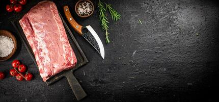 Raw pork on a cutting board with spices and a knife. photo