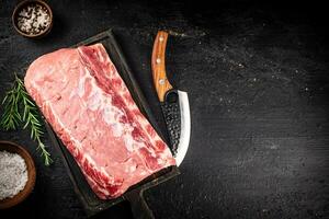 Raw pork on a cutting board with spices and a knife. photo