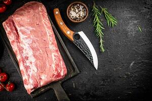 Raw pork on a cutting board with spices and a knife. photo