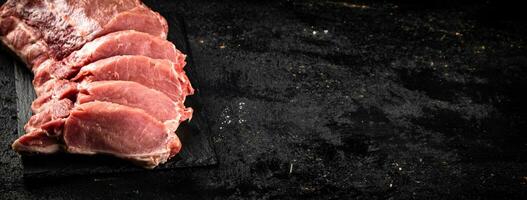 Pieces of raw pork on a stone board. photo