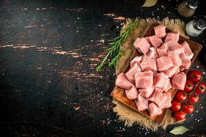 Pieces of raw pork on a wooden plate with spices and tomatoes. photo