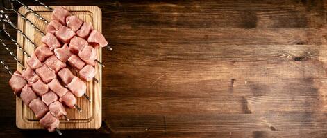 Pork kebab raw on skewers on a cutting board. photo