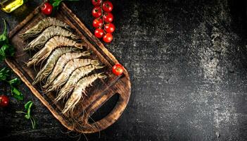 Raw shrimp on a cutting board with parsley and tomatoes. photo