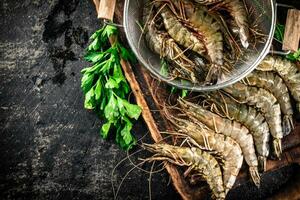 Raw shrimp in a colander and on a cutting board. photo