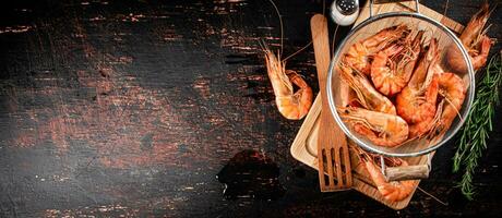 Boiled shrimp in a colander with a sprig of rosemary. photo