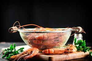 Boiled shrimp in a colander on a cutting board with parsley. photo