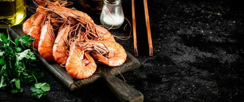 Boiled shrimp on a cutting board with parsley and spices. photo