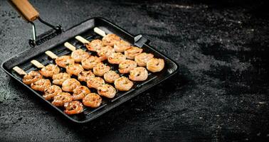 Shrimp on skewers are grilled in a grill pan. photo