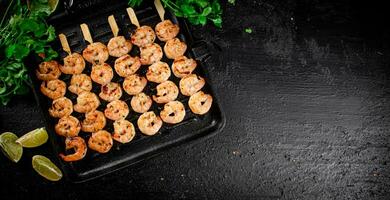 Grilled shrimp in a frying pan with parsley and pieces of lime. photo