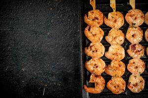 Shrimp on skewers are grilled in a grill pan. photo