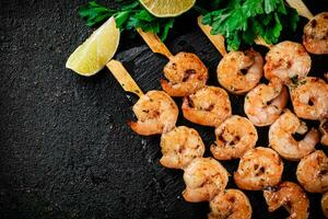 Grilled shrimp on a stone board with parsley and lime. photo