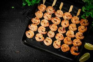 Grilled shrimp in a frying pan with parsley and pieces of lime. photo