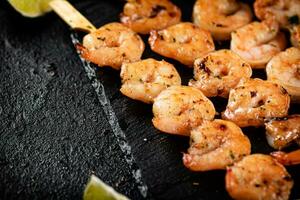 Grilled shrimp on a stone board with pieces of lime. photo