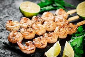 Grilled shrimp on a stone board with parsley and lime. photo