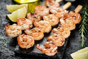 Grilled shrimp on a stone board with pieces of lime. photo