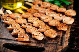 Grilled shrimp on skewers with parsley on a cutting board. photo