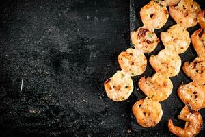 Delicious grilled shrimp on skewers on a stone board. photo