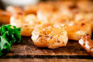 Grilled shrimp with parsley on a wooden background. photo