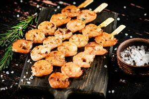 Delicious grilled shrimp on a cutting board with rosemary and spices. photo