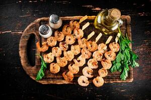 Grilled shrimp on skewers with parsley on a cutting board. photo