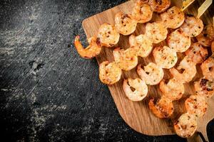 Grilled shrimp on a wooden cutting board. photo