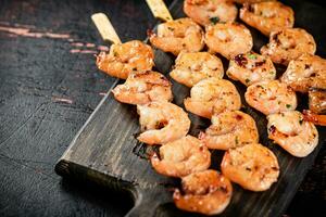 Grilled shrimp on skewers on a cutting board. photo