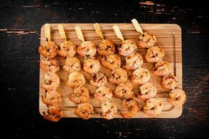 Grilled shrimp on skewers on a cutting board. photo