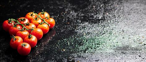 A branch of ripe tomatoes on a wet table. photo