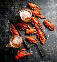 Boiled crayfish with beer on a cutting board. photo