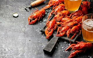 Boiled crayfish with beer on a cutting board. photo