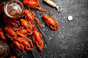 Boiled crayfish with beer on a cutting board. photo