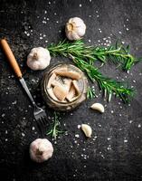 Salted herring on a wooden plate with garlic and rosemary. photo