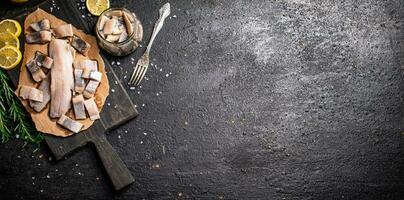 Fillet of salted herring on paper on a cutting board. photo