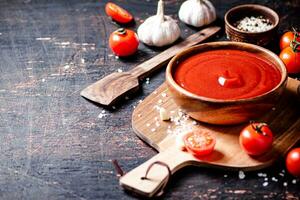 Tomato sauce on a wooden cutting board with garlic and spices. photo