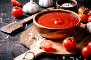 Tomato sauce on a wooden cutting board with garlic and spices. photo