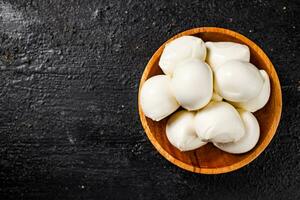 Mozzarella cheese in a wooden plate on the table. photo