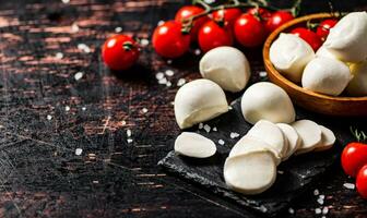 Sliced mozzarella on a stone board with tomatoes. photo