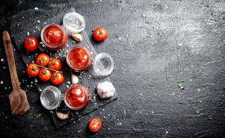 Tomato sauce in glass jars on a stone board with spices. photo