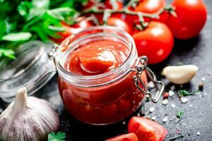 Tomato sauce in a glass jar with parsley and garlic. photo