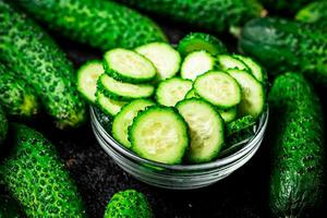 Sliced and whole cucumbers on the table. photo